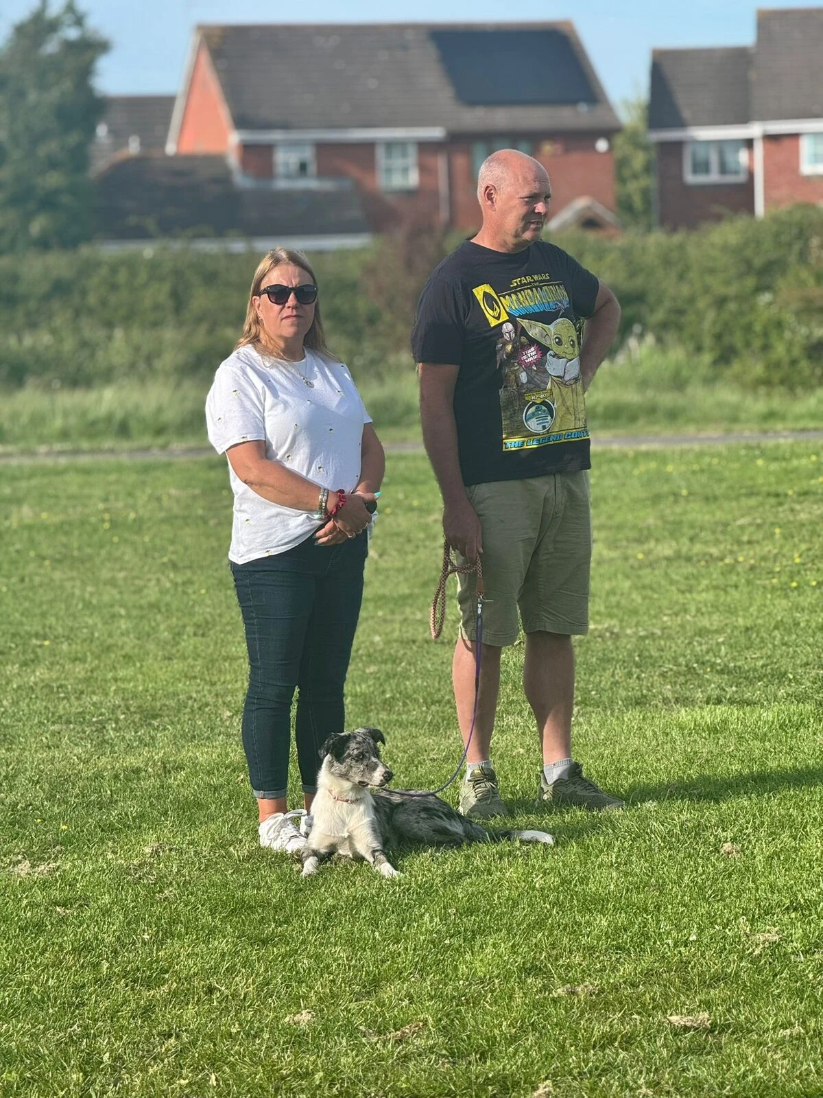 A couple standing in a field with their dog after a session