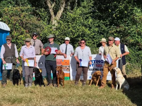 Handlers and dogs with rosettes at a gundog working test